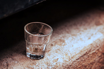 Small empty glass standing alone on concrete surface