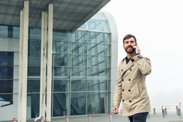 Businessman on the airport holding mobile phone.