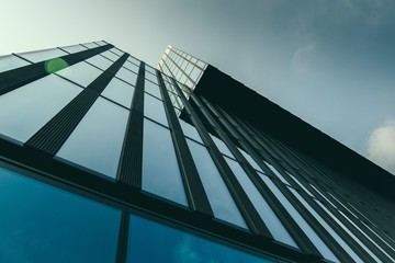 Low angle shot of a building in a glass facade under the beautiful cloudy sky