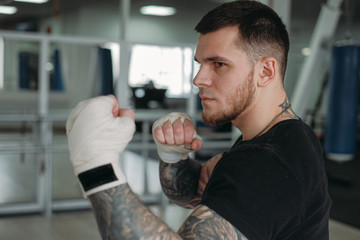 MMA and boxing training. Brutal, tattooed man boxing in a MMA training session in the gym.