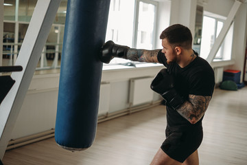 MMA and boxing training. Brutal, tattooed man boxing in a MMA training session in the gym.