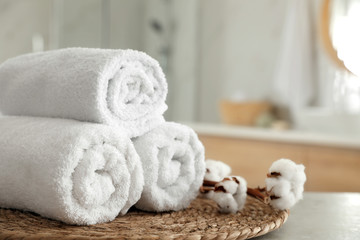 Obraz na płótnie Canvas Clean rolled towels and cotton flowers on table in bathroom