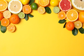 Juicy citrus fruits and leaves on yellow background, space for text