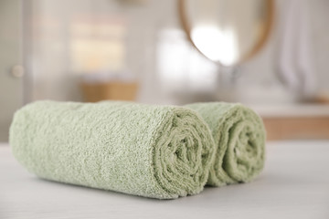 Fototapeta na wymiar Clean rolled towels on white wooden table in bathroom