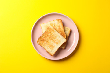 Plate with tasty toasts on yellow background, top view