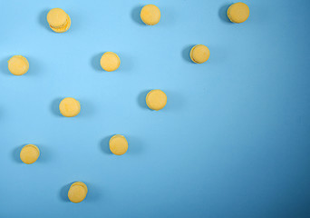 Yellow macaron lie in rows diagonally against a blue background. pattern, horizontal view, flat lay
