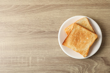 Plate with toasts on wooden background, top view