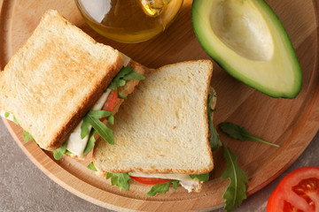 Delicious sandwiches, oil, avocado and tomato on grey table, top view