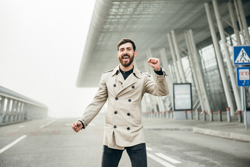 Cheerful and Happy Businessman is Actively Dancing on a Street . He's Wearing a Grey Suit. Sunny Day.