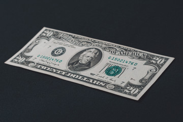 One twenty dollar bill isolated on a black background.