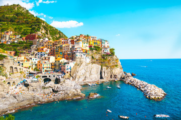 Naklejka premium A beautiful landscape of the Manarola village of Cinque Terre located in northern Italy and the blue sea with yachts and boats