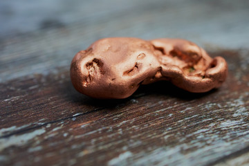 macro of copper nugget against wooden surface with copy space