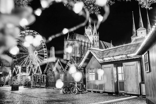 Abstract festive photo with blurred lights. Christmas market, ferris wheel and famous cathedral Dom hill at night. Erfurt, Germany. Black and white