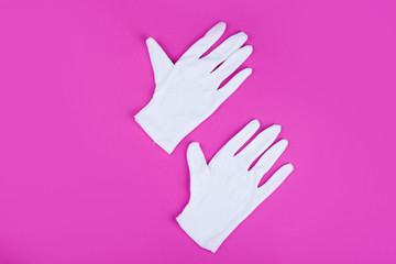 Two white gloves on a pink background. Stylish content