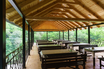 The interior of an open cafe over the river in the mountains. Wooden tables and benches