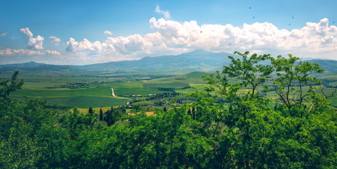 Fantastic summer field in Italy, Tuscany landscape with cloudy sky and fragment of stone wall.View of fields and hills of Tuscany from above the walls