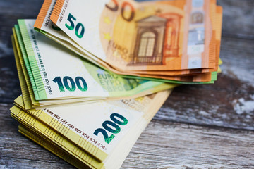 pile of fifty, hundred and two hundred Euro banknotes on wooden surface