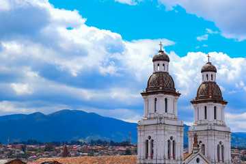 View of old two towers that adorn a church, protruding over the red roofs of the houses.