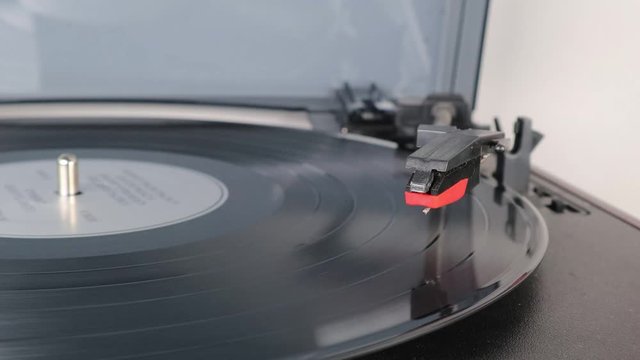 Macro shot of record needle dropping and playing record on turntable as vinyl record spins isolated studio background turntable music