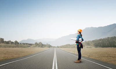 Young woman in safety helmet standing on road
