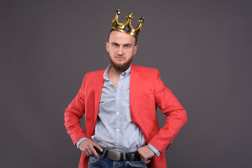 Portrait of self-confident male in red jacket with crown on his head. - obrazy, fototapety, plakaty