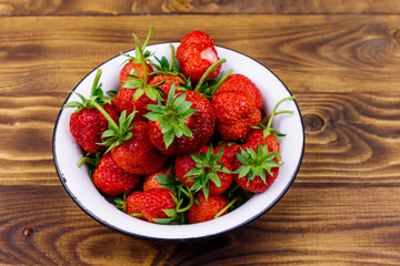 Fresh ripe strawberry in white bowl on a wooden table