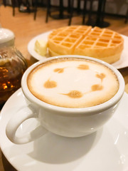 white a cup of coffee latte art with waffle and honey on wood background, selective focus