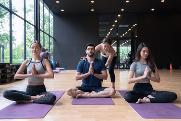 Group of multi ethnics people learning Yoga class in fitness club.