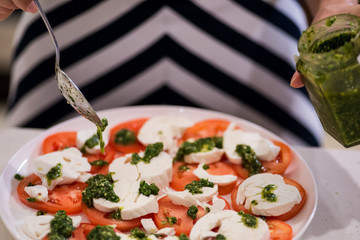 Adding pesto to a tomato and cheese salad