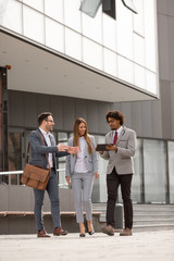 Three people standing in front of a corporate building.