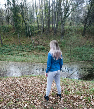 Blonde girl looks at a mountain river in the forest.