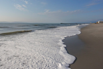White waves roll up on a beach on a beautiful sunny day