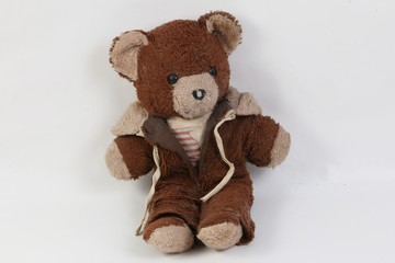 old brown damaged teddy bear is sitting in the white studio