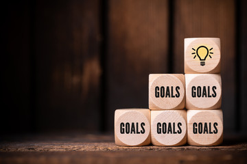 cubes with the word goals and a lightbulb symbol on wooden background