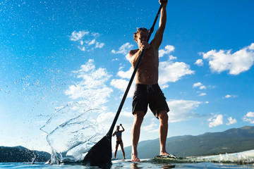 Two people stand up Paddleboarding, Whitefish Lake, Whitefish, Glacier Country, Montana, USA.