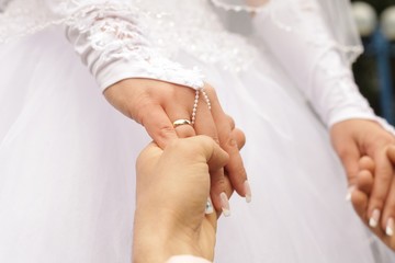 The guy holds the hands of a girl in a white dress close-up
