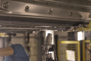 Production line of automobile plant, painting shop. Applying sealant to the bottom of the car body