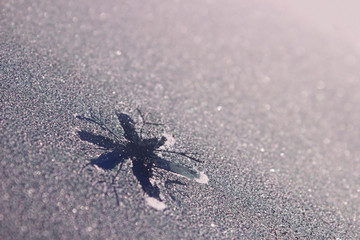 Snowflake painted on frozen window. A patterned snowflake is drawn with a finger on the hoarfrost. Snowflake on winter window