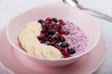 Smoothie bowl with banana, blackcurrant, pomegranate seeds, oatmeal and chia seeds