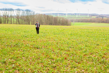 Lady is speaking on the phone while standing in an open field during a cold winter afternoon.