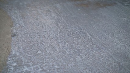 The hand of a man holding a roller and puts primer on concrete floor. Primer for concrete floors
