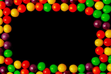 Frame of colorful jelly bean candies on black background. Copy space in the middle.