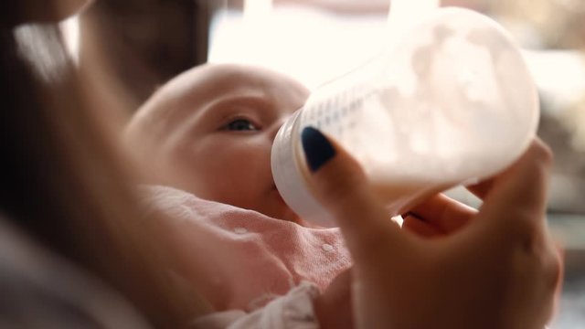 mom feeds the baby from the bottle
