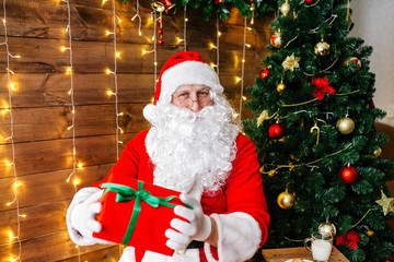 Merry Christmas. Santa Claus near Christmas tree with gifts and lights
