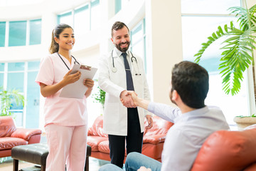 Fototapeta premium Healthcare Workers Greeting Man Waiting At Hospital