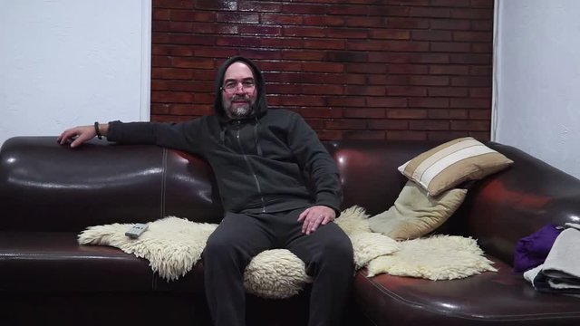 Bearded man switches the TV channels while sitting on the couch