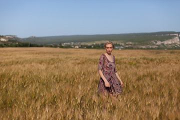 Naklejka na ściany i meble Beautiful fashionable blonde woman in a field of rye