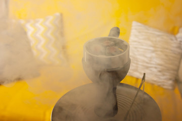 Fototapeta na wymiar Recreation and entertainment. Hookah, coals and smoke in a relaxing environment