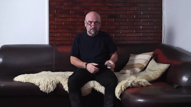 Bearded man switches the TV channels while sitting on the couch