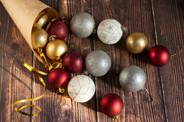 Fototapeta na wymiar Christmas gifts, gold, silver, red Christmas balls spilled out from a package of kraft paper on a wooden background. Christmas balls. Copyspace.